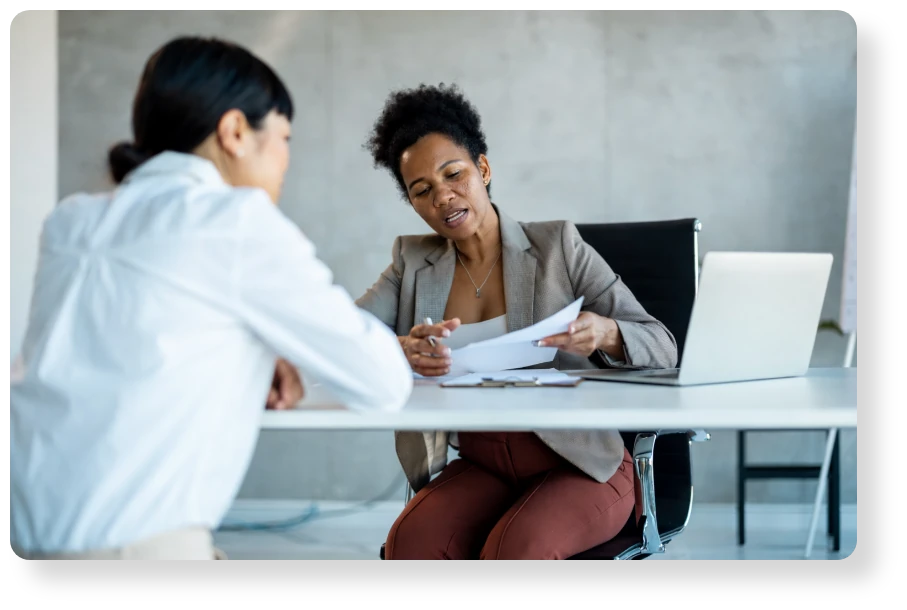 Two business professionals reviewing documents during a one-on-one meeting in a modern office.