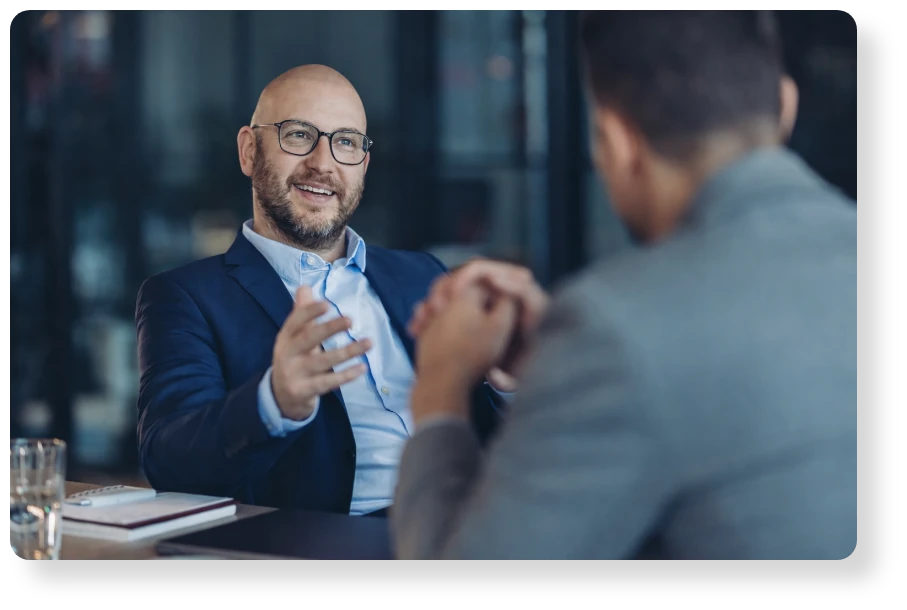 A business professional speaking and gesturing during a one-to-one conversation in a modern office.