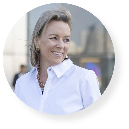 Smiling business professional in a white shirt, looking to the side in a modern office.